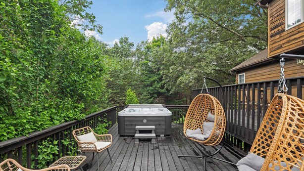 Een houten terras met wickerstoelen en een jacuzzi.