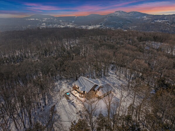 Paisaje nevado con una cabaña que cuenta con una terraza grande y un jacuzzi.