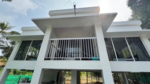 A modern building with a flat roof, large windows, and a balcony with white railings. - Charming 2-Bedroom Riverfront Cottage In Pleasant Pala With WiFi, AC (Pala)