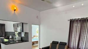 A modern living room with a sofa, a coffee table, and a kitchen area with a microwave. - Charming 2-Bedroom Riverfront Cottage In Pleasant Pala With WiFi, AC (Pala)