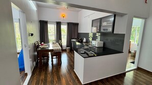 A modern kitchen with a central island, a dining area with a table and chairs, and a view of the outdoors. - Charming 2-Bedroom Riverfront Cottage In Pleasant Pala With WiFi, AC (Pala)