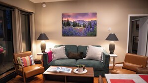 A living room with a green sofa, two armchairs, a coffee table, and a painting of a mountain landscape. - Edelweiss MTN Haus, Summer Base Camp Steps from PCMR, Pool, Hot Tub. Local Hosts (Park City)