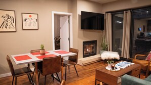 A modern living room with a dining area, a fireplace, and a TV mounted on the wall. - Edelweiss MTN Haus, Summer Base Camp Steps from PCMR, Pool, Hot Tub. Local Hosts (Park City)