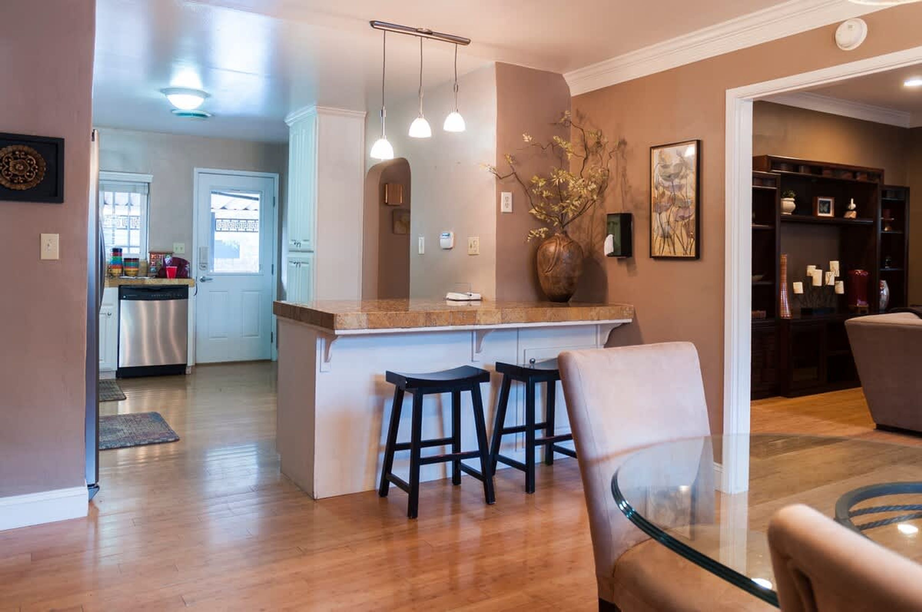A modern kitchen with a central island, bar stools, and pendant lighting.