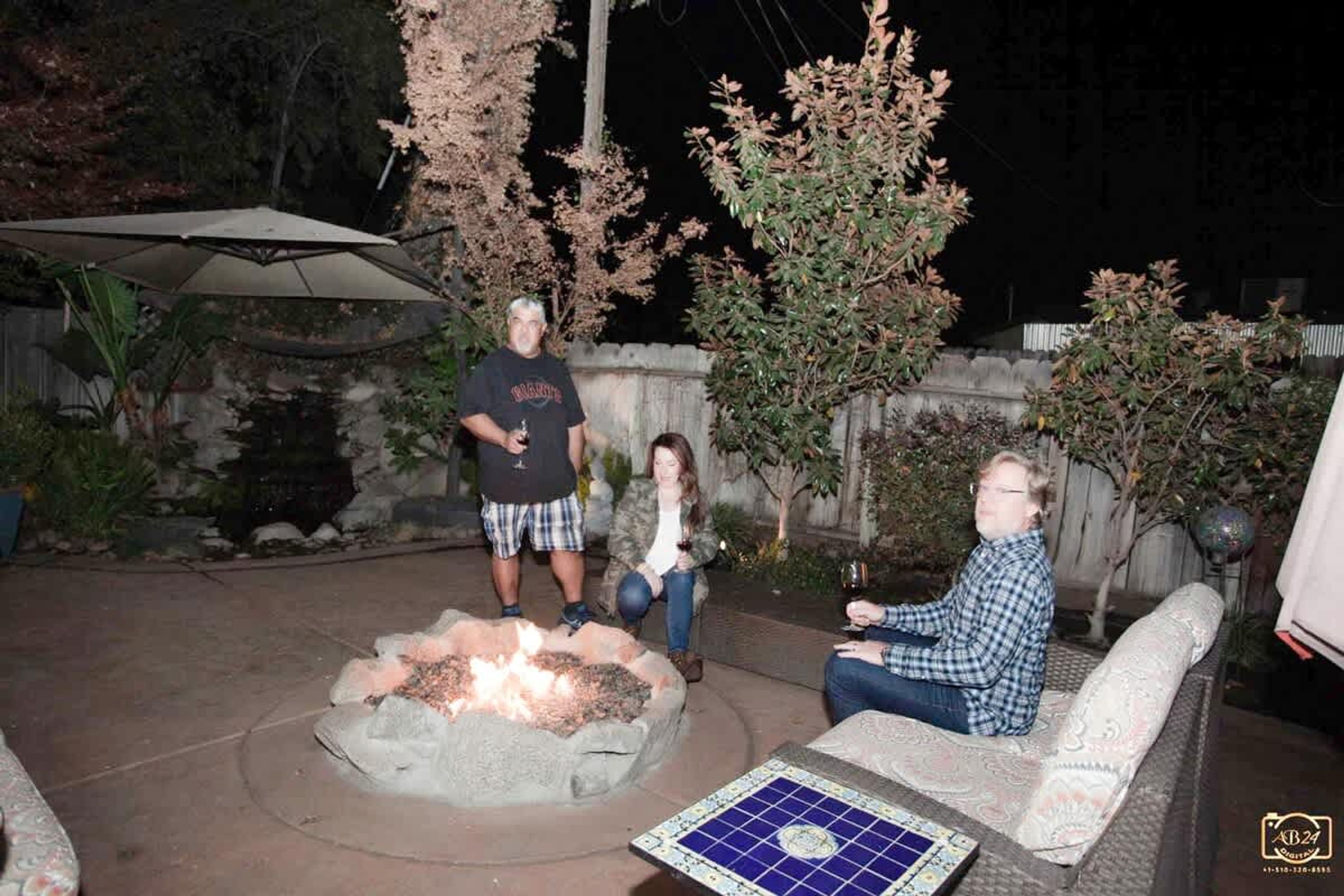 An outdoor patio area with a fire pit, seating, and a tiled table.