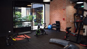 Une salle de sport équipée de matériel d’exercice, dotée d’une grande fenêtre et d’un mur en briques.