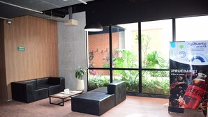 Un hall d’entrée moderne avec un canapé en cuir noir, une table basse et une grande fenêtre donnant sur un paysage verdoyant.