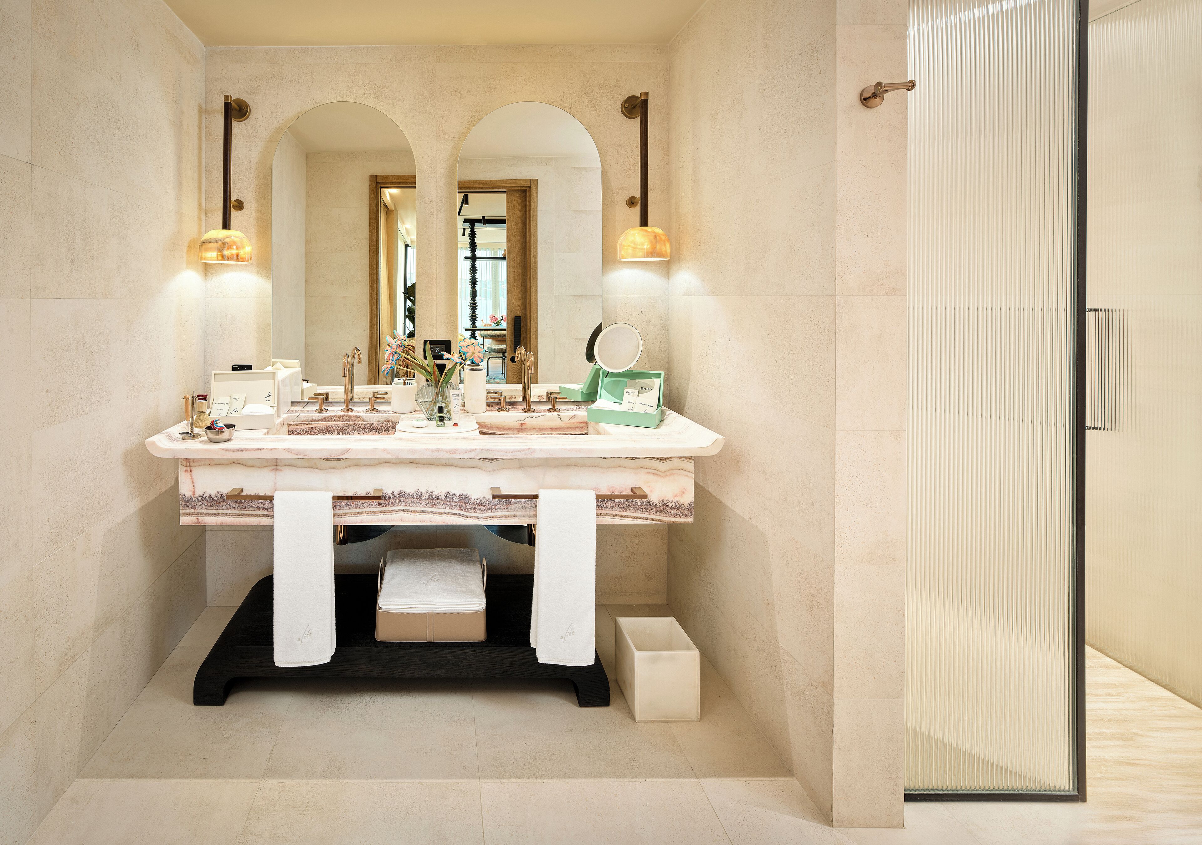 A modern bathroom with a marble vanity, two sinks, a large mirror, and a walk-in shower.