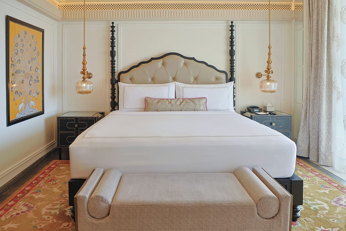 Una cama grande con cabecera capitonada, dos mesitas de noche y un elemento decorativo en la pared.