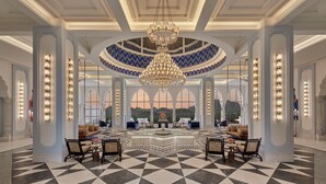 A grand lobby with a geometric patterned floor, a central chandelier, and seating arrangements. - Fairmont Udaipur Palace (Udaipur)