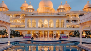A grand hotel with multiple domed structures, a central courtyard with a pool, and a series of balconies. - Fairmont Udaipur Palace (Udaipur)