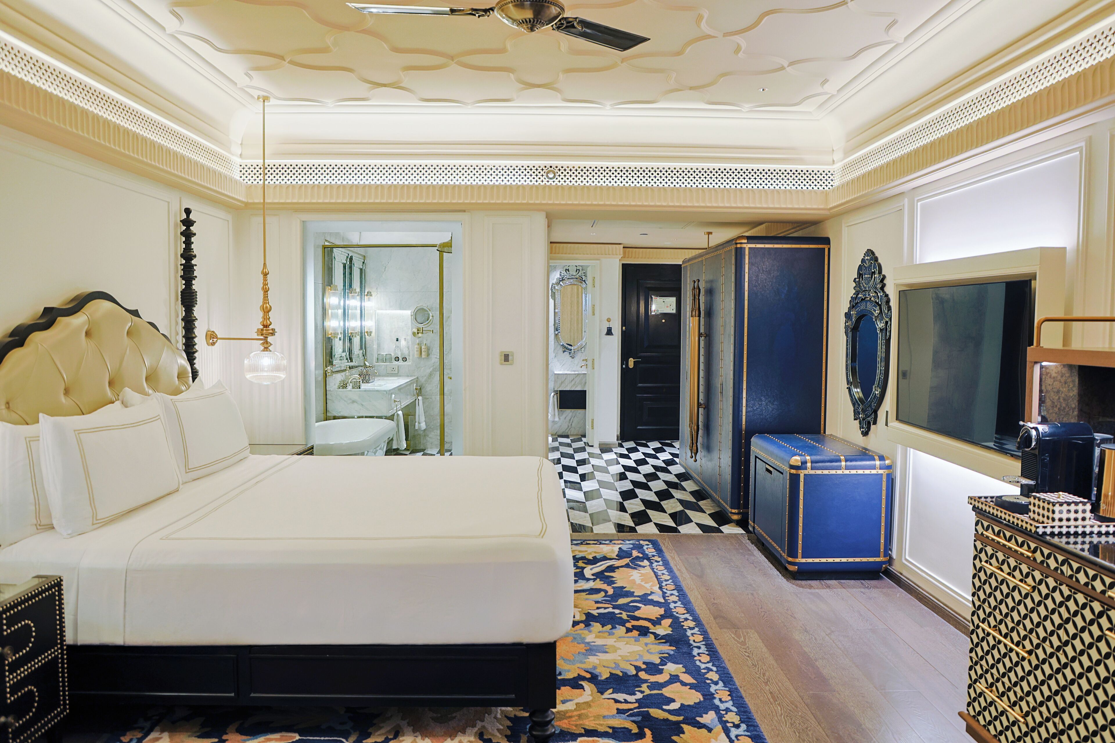 A hotel room with a large bed, a television, a wardrobe, and a bathroom visible through an open door.