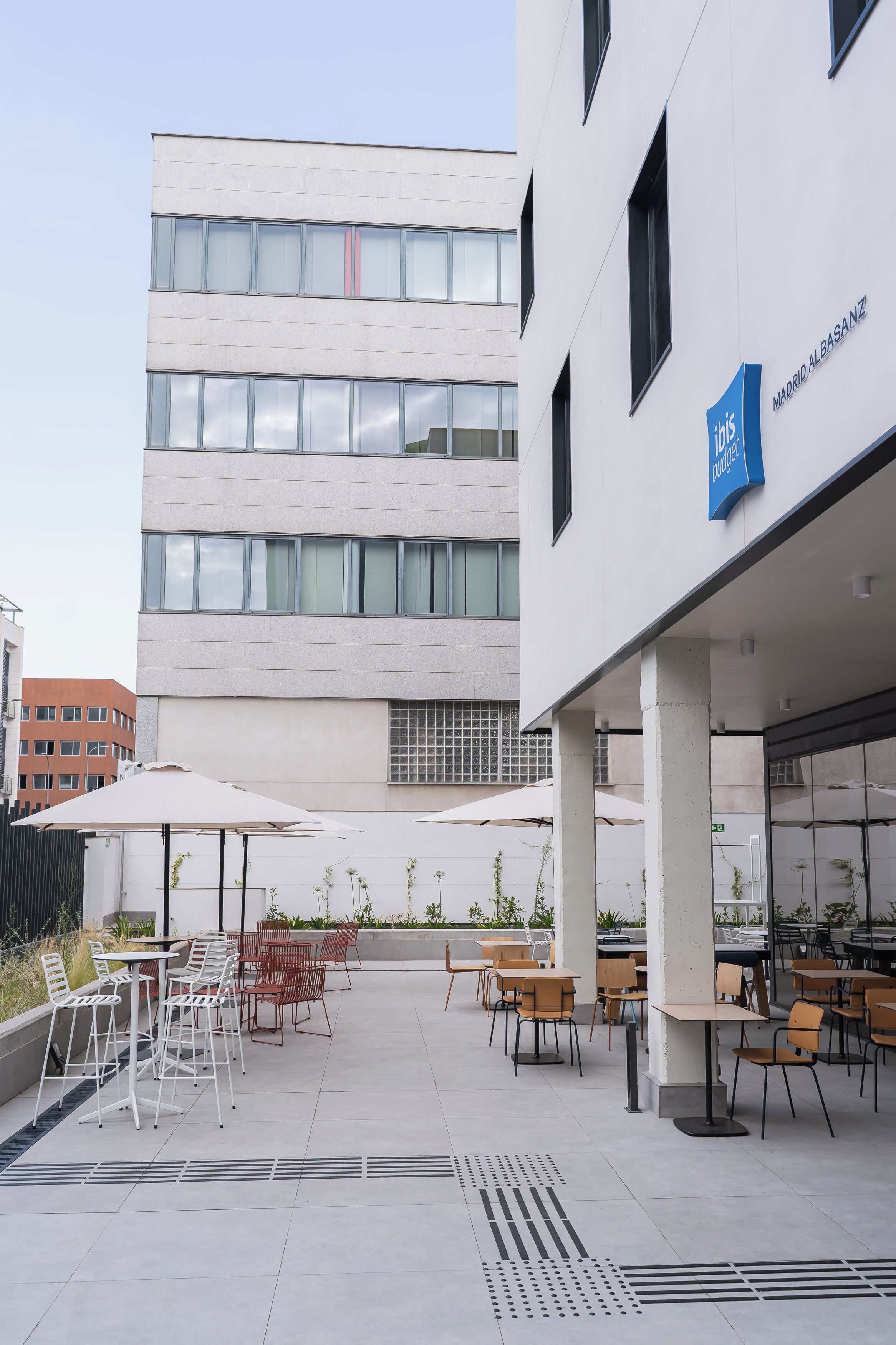 Un espacio al aire libre con mesas y sillas, un edificio con un letrero y un cielo despejado.