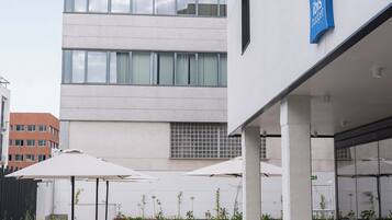 Un espacio al aire libre con mesas y sillas, un edificio con un letrero y un cielo despejado.