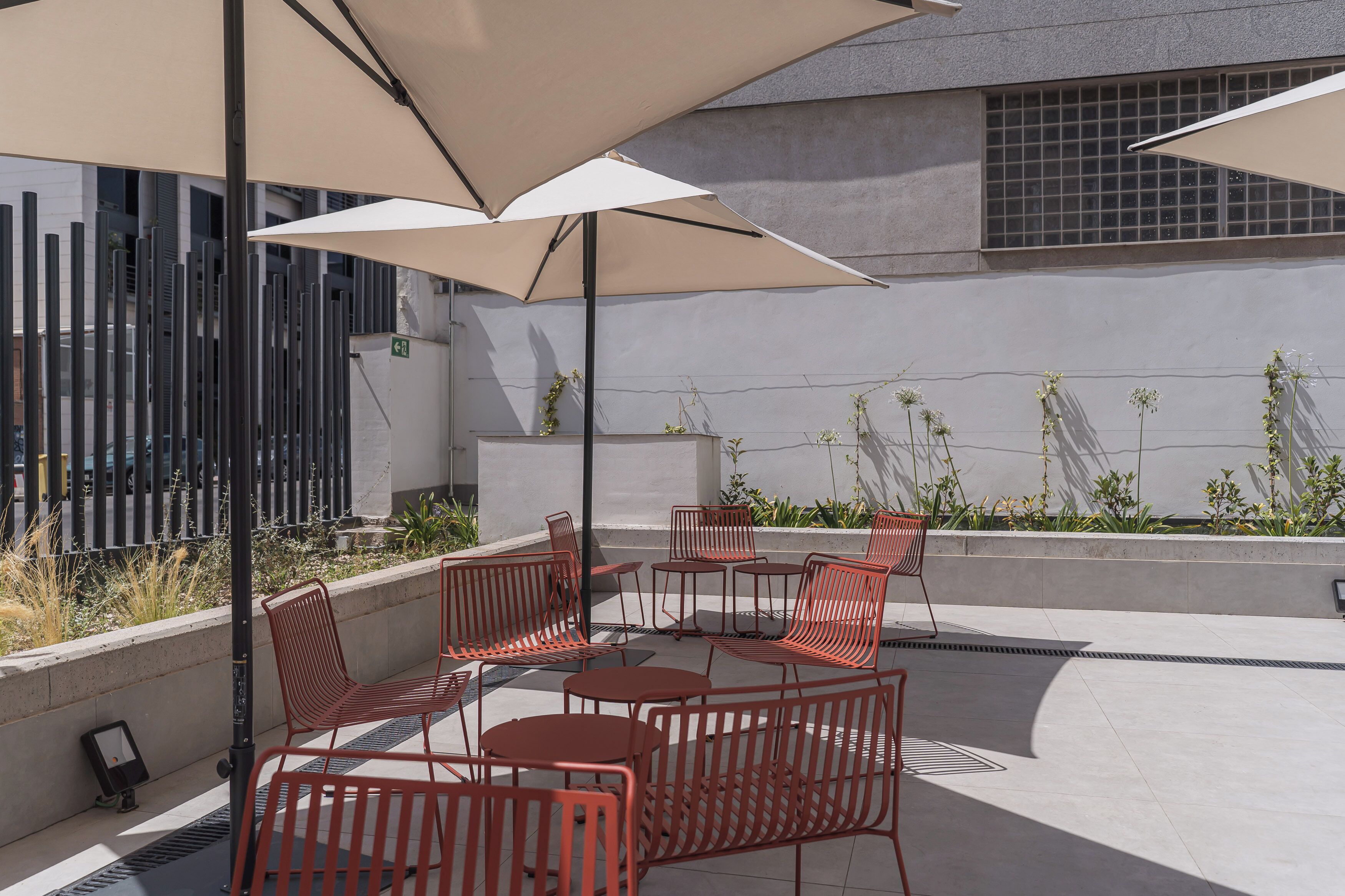 Outdoor seating with tables and chairs, a large umbrella, and a building in the background.