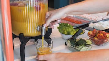 A person pouring orange juice from a pressurized container into a glass.