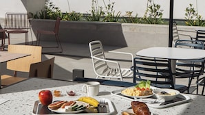 An outdoor dining area with tables, chairs, and a variety of food items.