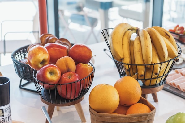 A table with a basket of apples, a basket of bananas, and a bowl of oranges.