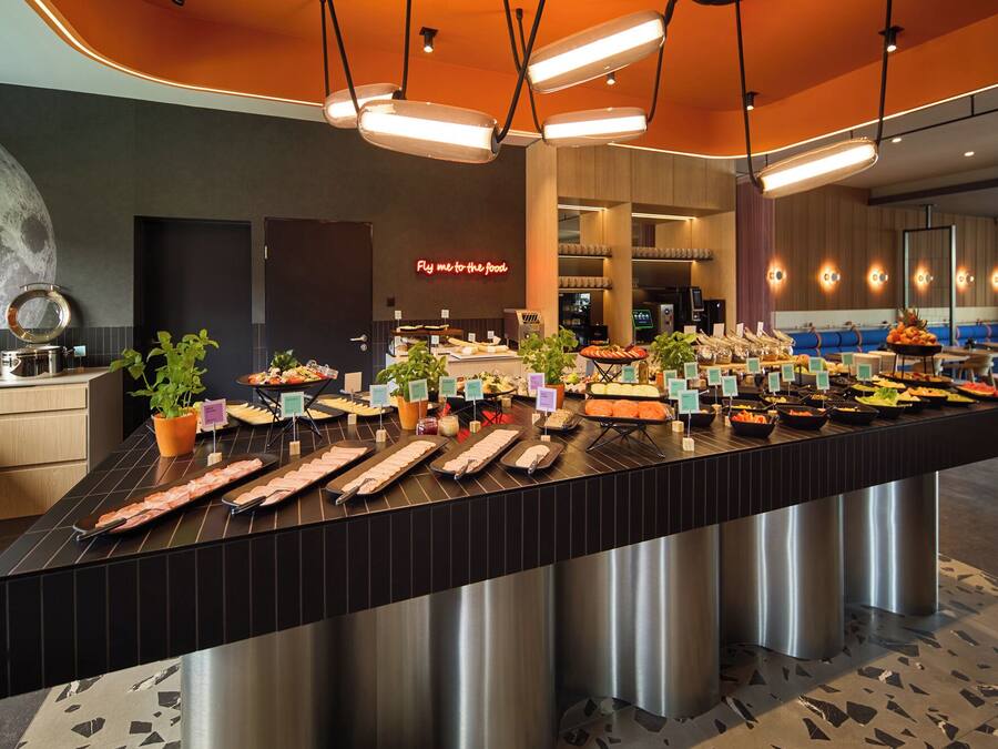 Un buffet proposant une variété de plats, agrémenté d'une pancarte indiquant : « Venez vous servir ! » ou « Dégustez à volonté ! ».