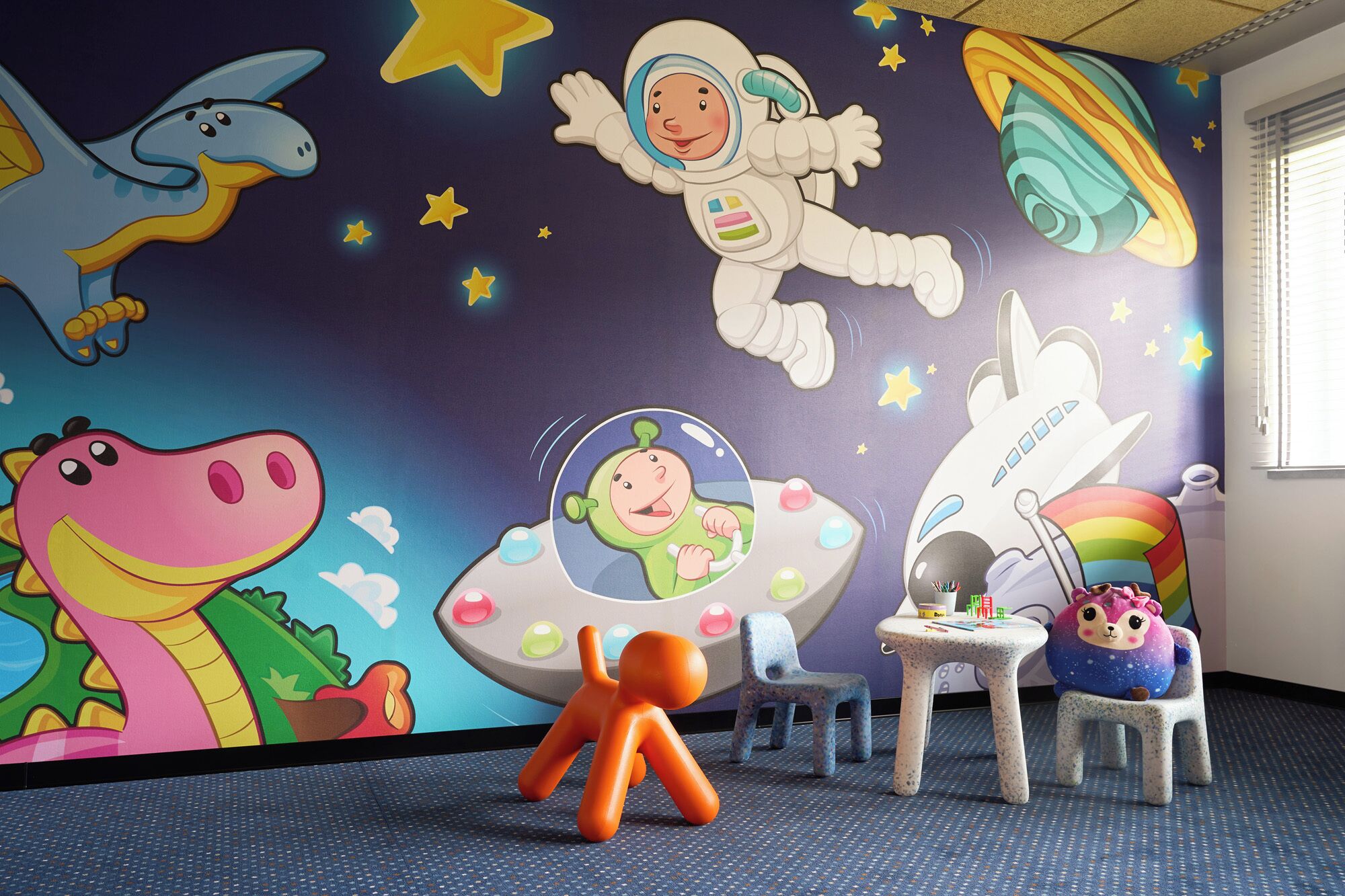 A children's playroom with a space-themed mural, a dinosaur toy, and a small orange figure.