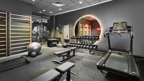 Une salle de sport équipée de matériel d’exercice, de bancs, d’un tapis de course et d’un sac de frappe.