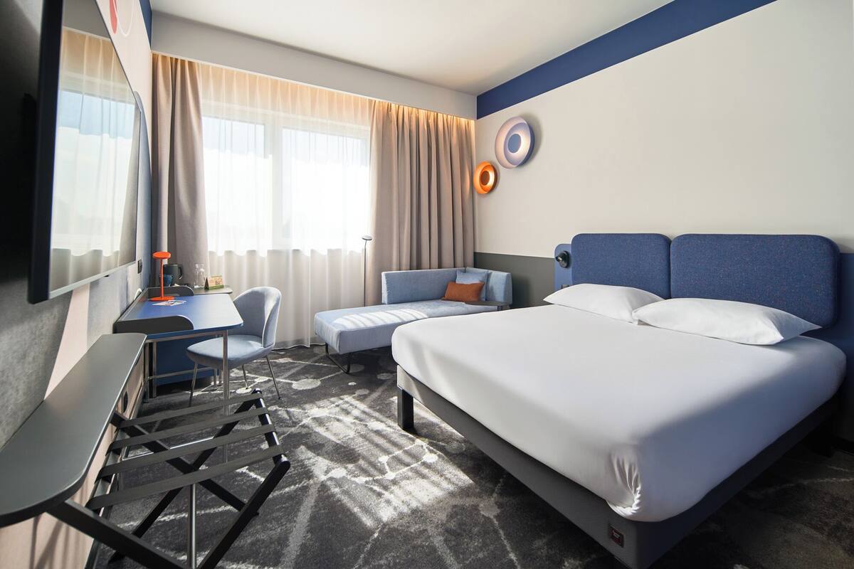Una habitación de hotel con cama, escritorio, silla y sofá.