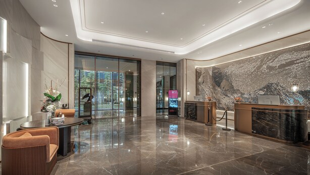 Eine moderne Lobby mit einer Rezeption, einer Sitzecke und einer großen Marmorwand.