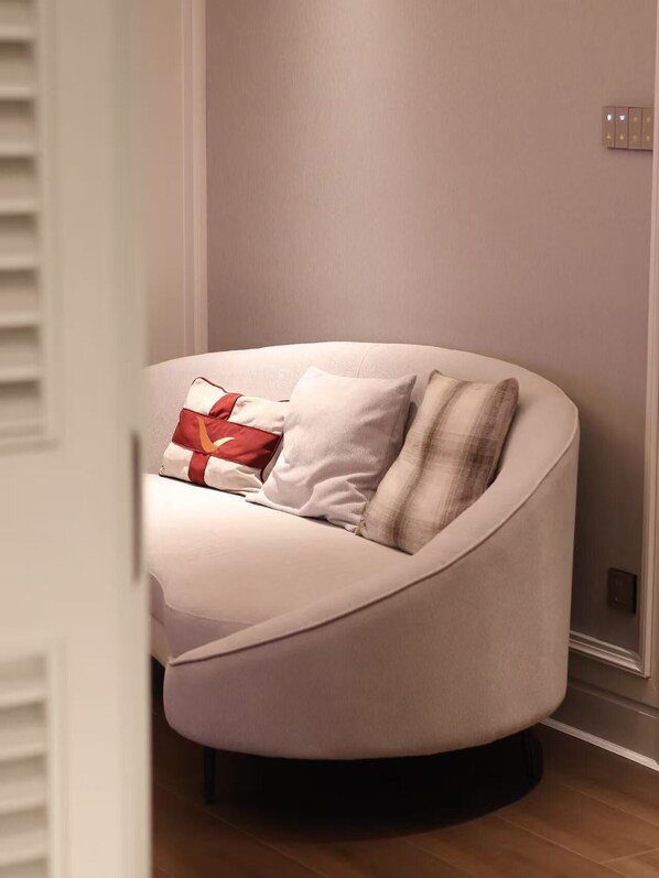 Ein modernes, gebogenes Sofa mit Kissen und Nackenkissen in einem Raum in neutralen Farbtönen.