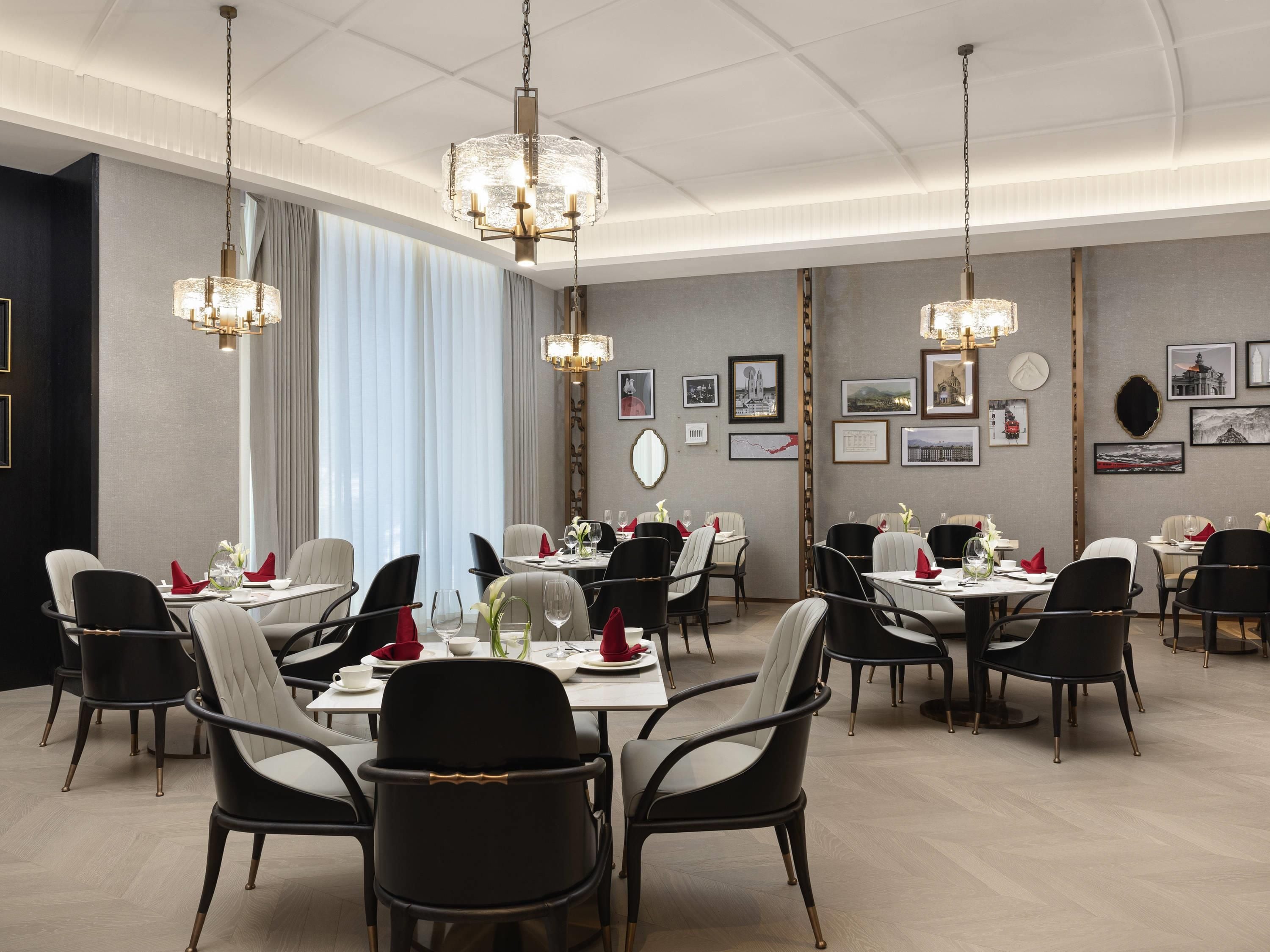 Un comedor con varias mesas y sillas, candelabros y cuadros en las paredes.