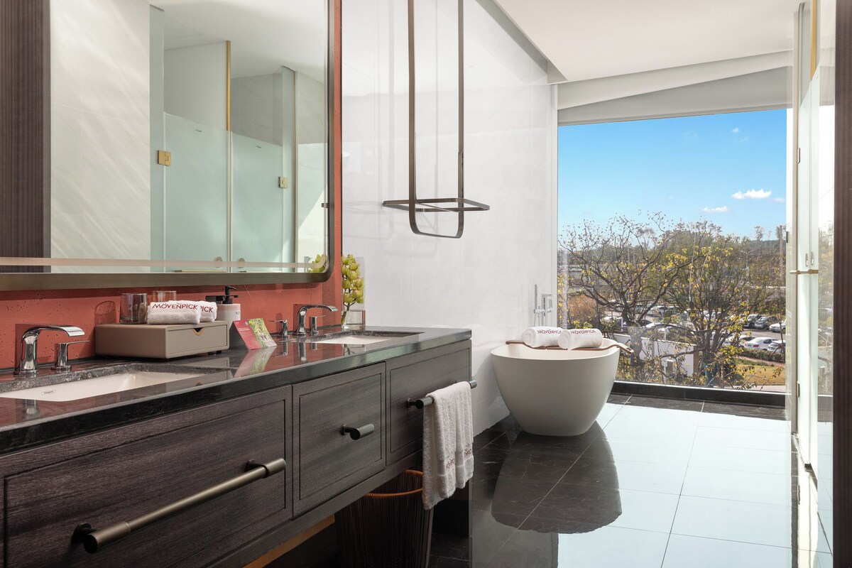 Un baño moderno con lavamanos dobles, un espejo grande y una bañera independiente.