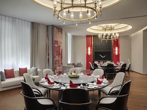 A modern dining room with a round table set for six, surrounded by black and white chairs.