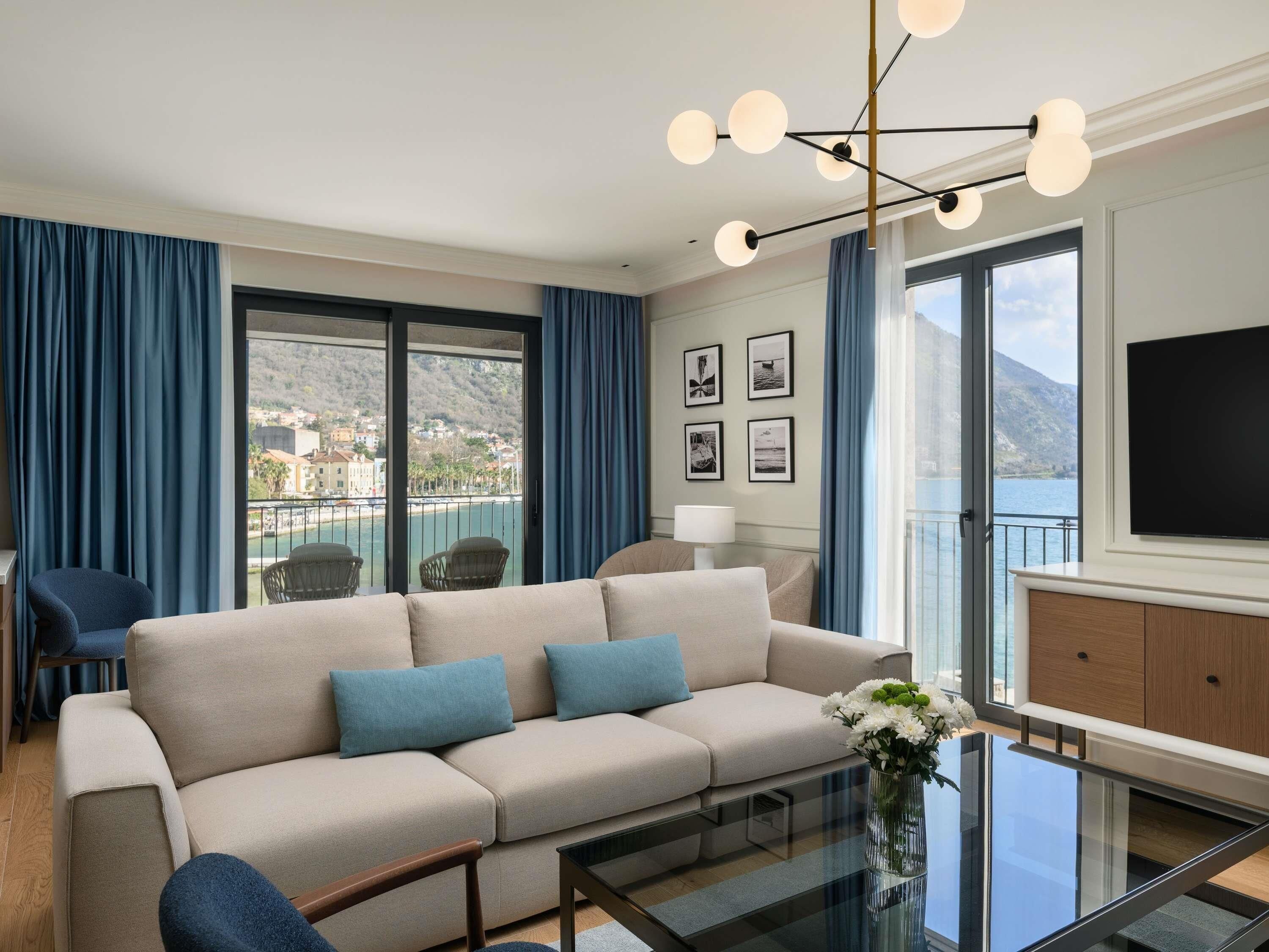 Una sala de estar moderna con un sofá, sillones, una mesa de centro de vidrio y vista al mar.