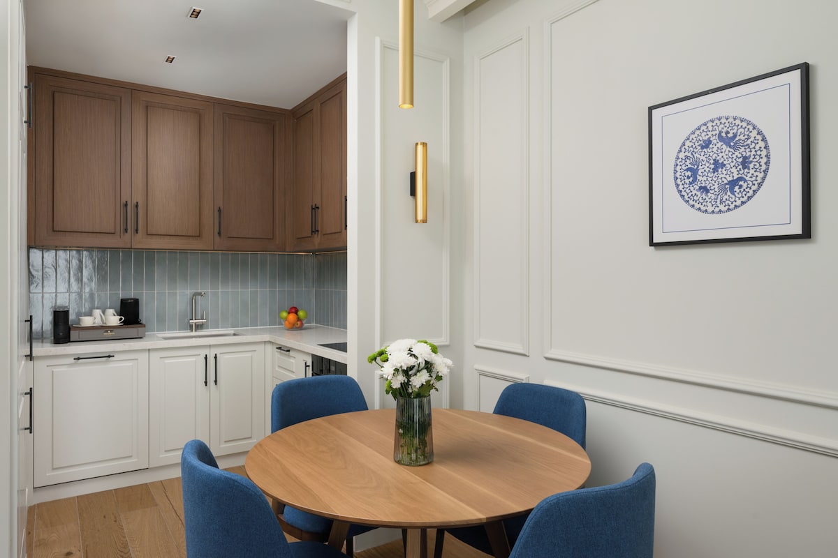 A modern kitchen with white cabinets, a wooden dining table, and blue chairs.