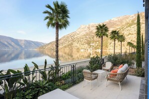 Una terraza con mobiliario exterior, vista a un lago y montañas al fondo.