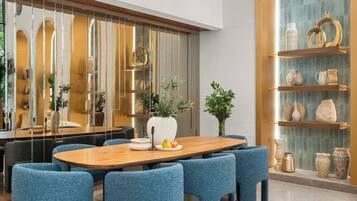 Un comedor moderno con una mesa de madera, sillas tapizadas en azul y jarrones decorativos en estantes.