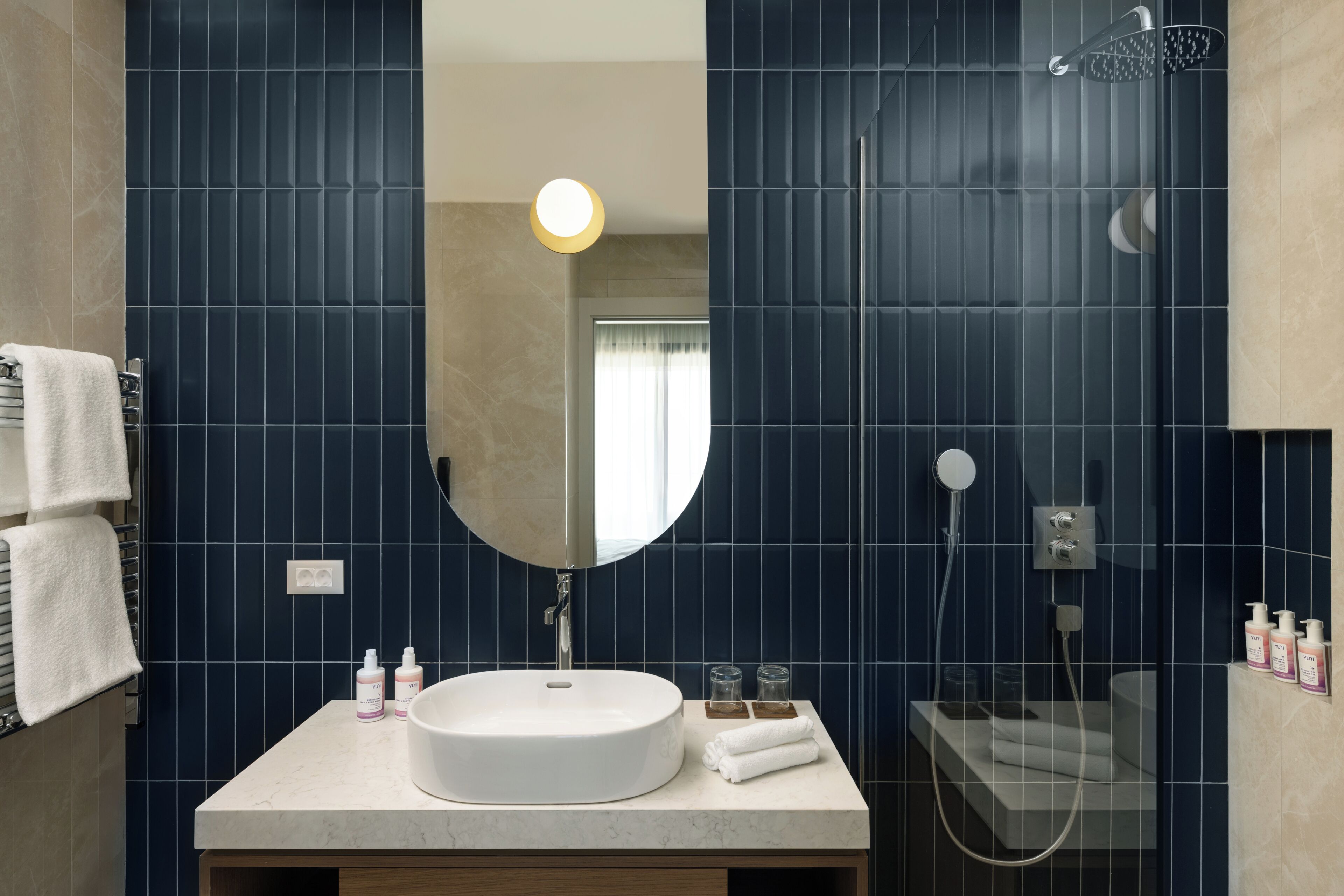 Un baño con un lavabo redondo, un espejo grande y una ducha.