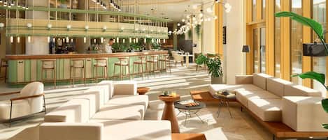 Un área de bar moderna con mostrador, asientos e iluminación colgante.