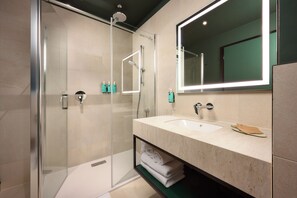 A modern bathroom with a glass-enclosed shower, a large mirror, and a vanity with a sink and towel rack. - Novotel Zagreb - opened September 2025 (Zagreb)
