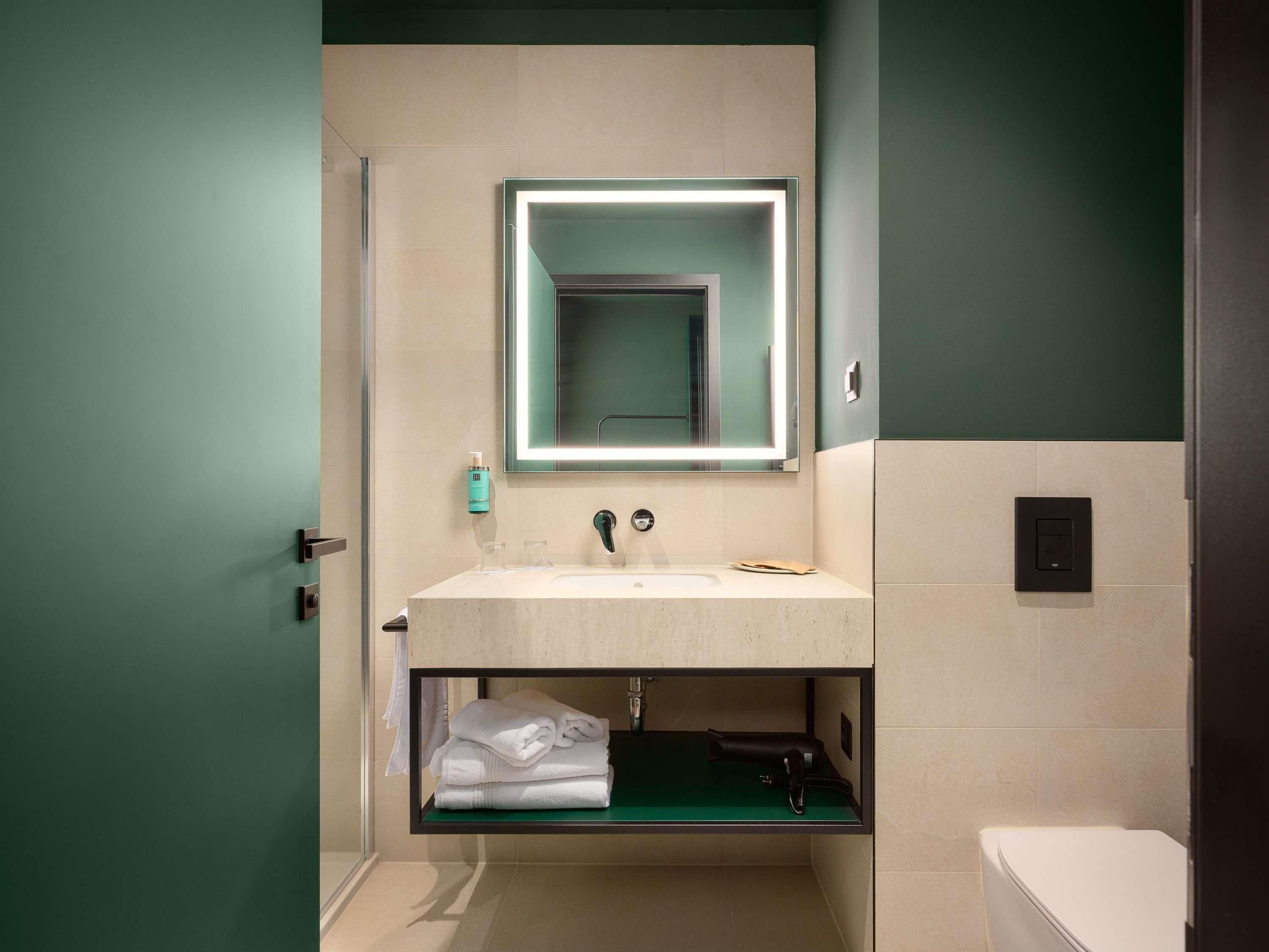 A modern bathroom with a vanity, a mirror, a towel rack, and a toilet.
