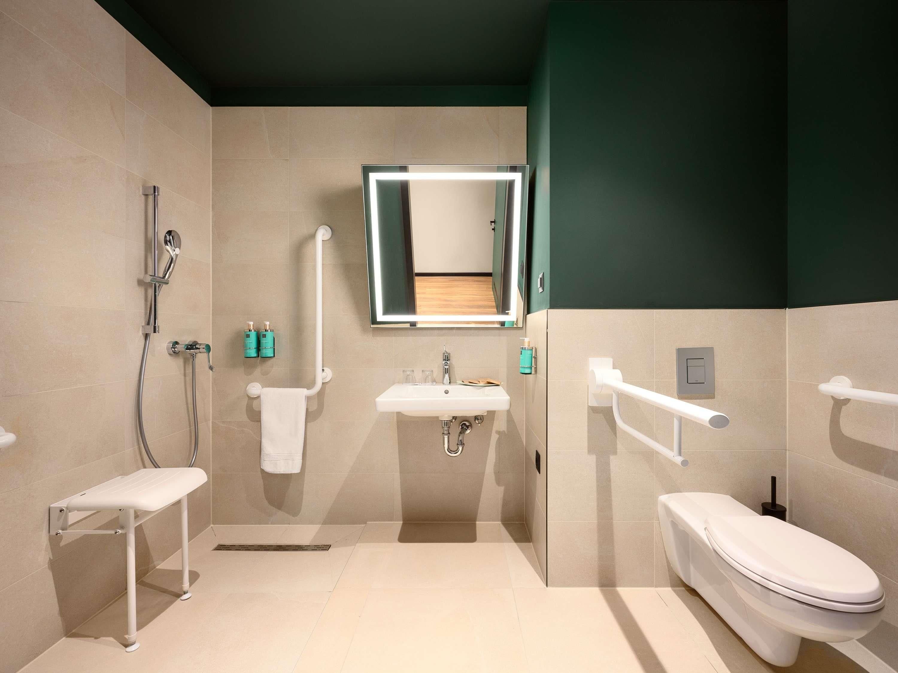 A modern bathroom with a shower, sink, toilet, and a mirror.