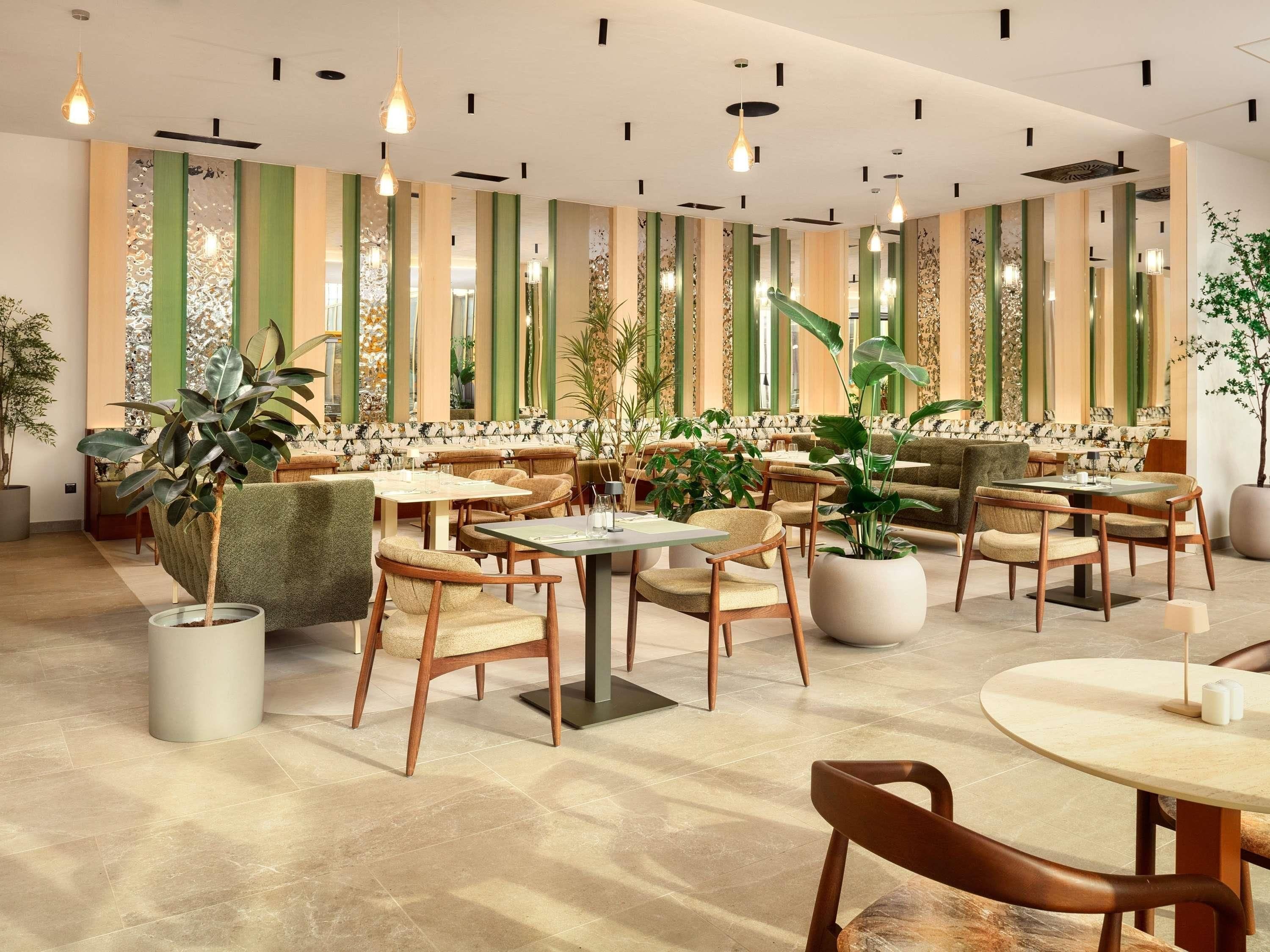A modern interior with multiple seating areas, including sofas and tables, and decorative plants.