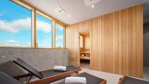 A modern spa room with two sun loungers, a large window, wooden panel walls, and a visible sauna area. - Novotel Zagreb - opened September 2025 (Zagreb)