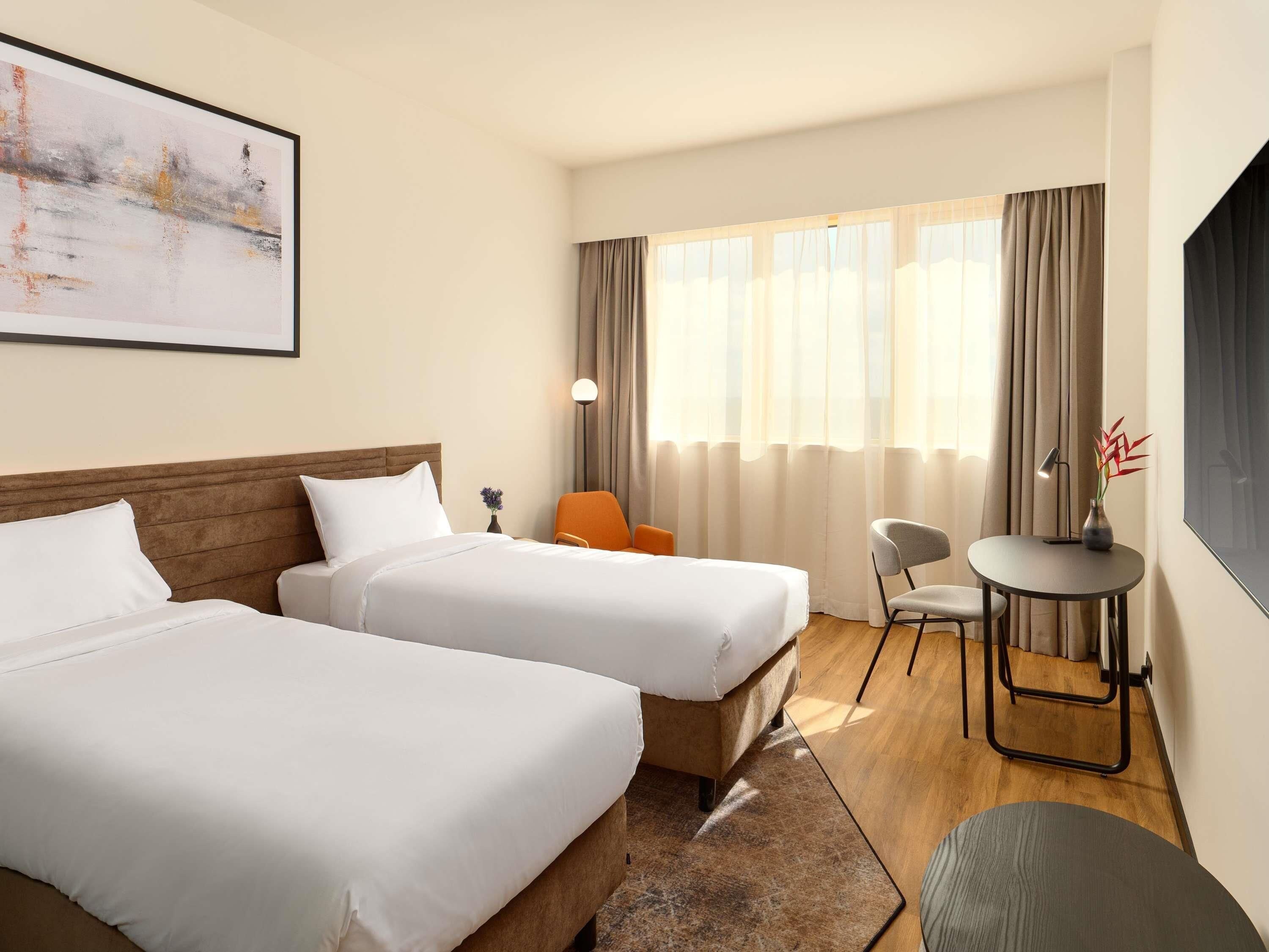 A hotel room with two beds, a desk, and a chair.