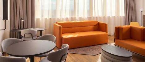 A modern living room with a sofa, chairs, a small table, and a lamp.