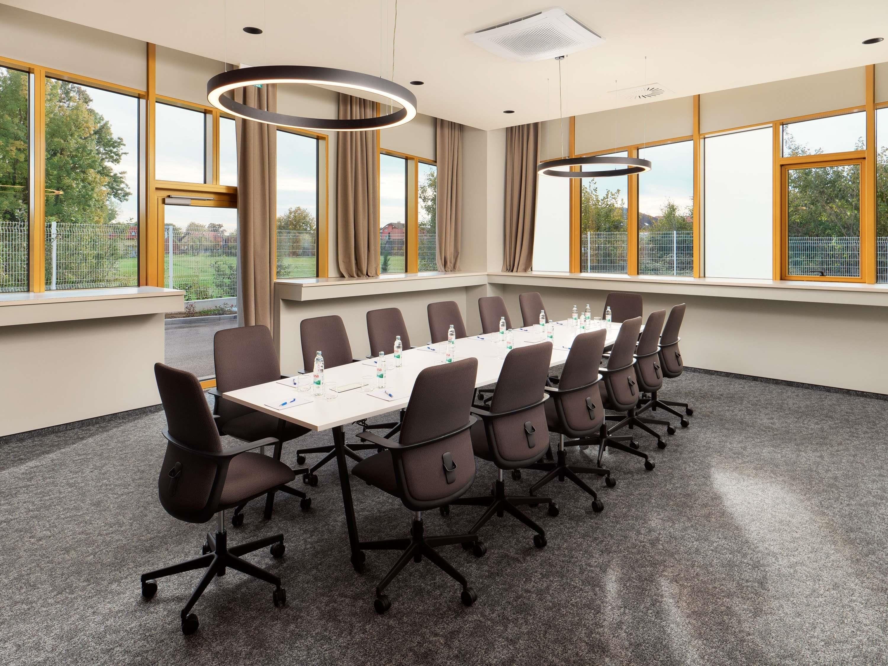 Una sala de conferencias con una larga mesa, sillas y ventanas amplias.