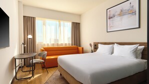 A hotel room with a large bed, a sofa, a small table, and a chair. - Novotel Zagreb - opened September 2025 (Zagreb)