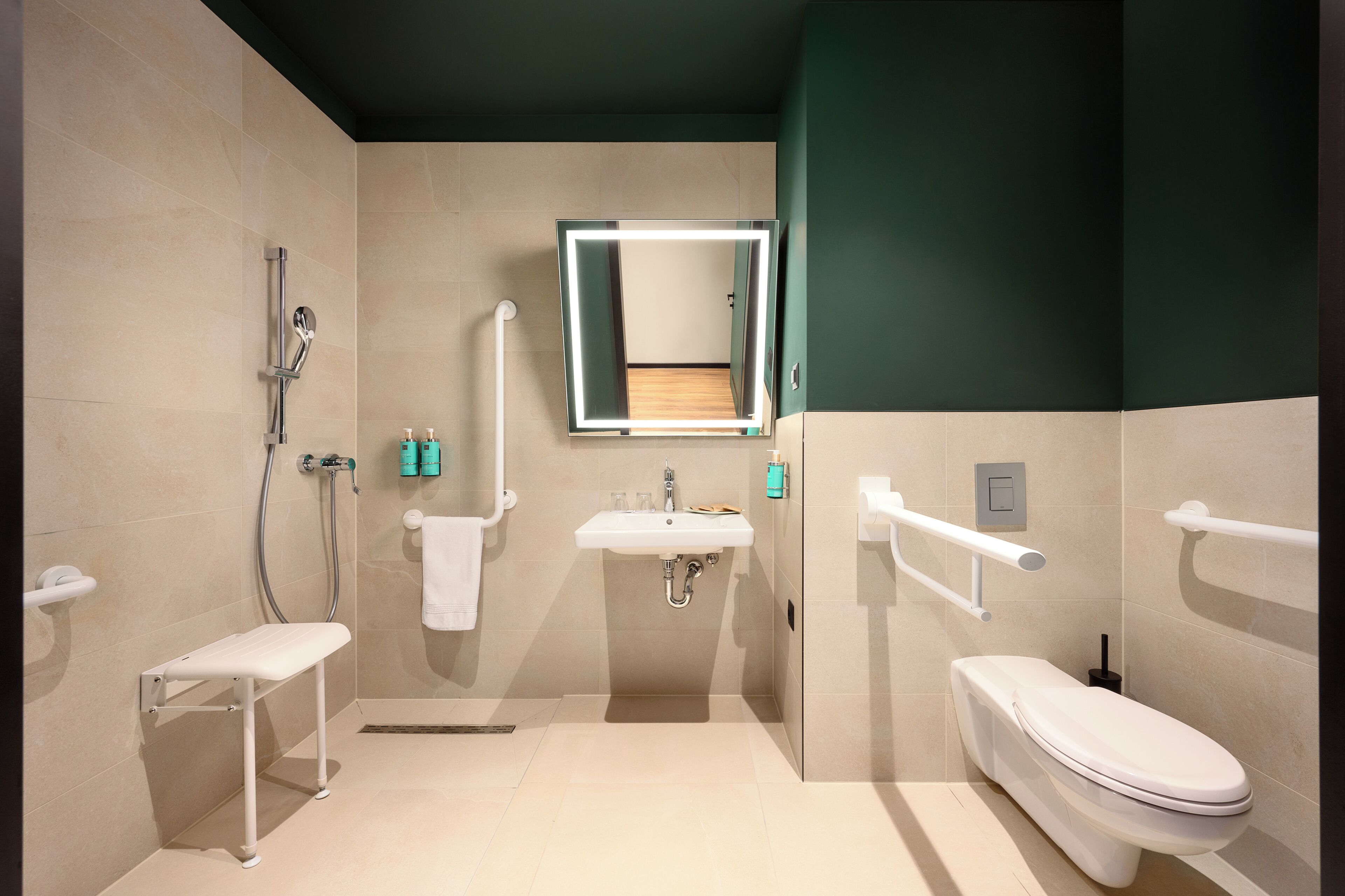 Un baño moderno con ducha, lavabo, inodoro y espejo con iluminación integrada.