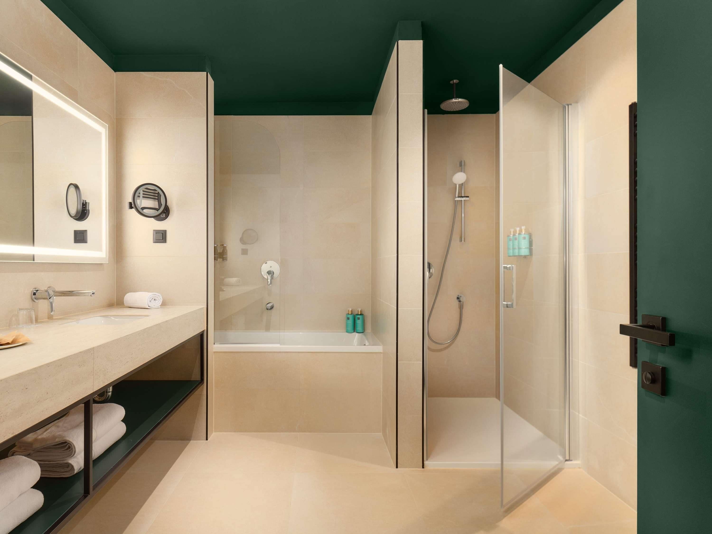 Un baño moderno con ducha envuelta en vidrio, una bañera, un tocador con espejo y un perchero para toallas.