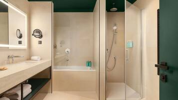Un baño moderno con ducha envuelta en vidrio, una bañera, un tocador con espejo y un perchero para toallas.