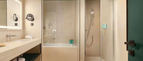 A modern bathroom with a glass-enclosed shower, a bathtub, a vanity with a mirror, and a towel rack.